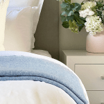 Neatly made bed with flowers on bedside table