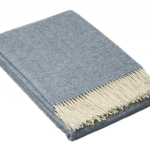 Folded blue throw blanket with cream fringe