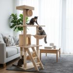 Three cats playing on beige cat tree indoors