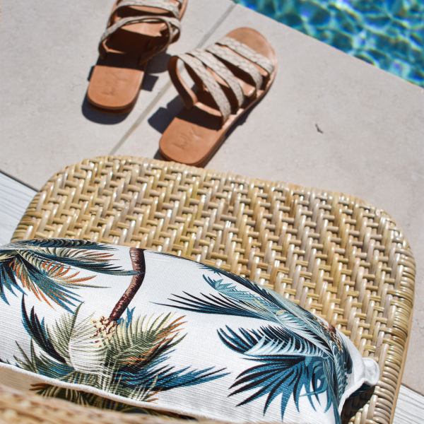 Woven poolside chair with sandals and tropical cushion