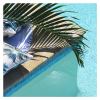 Palm leaf shadow over poolside cushions