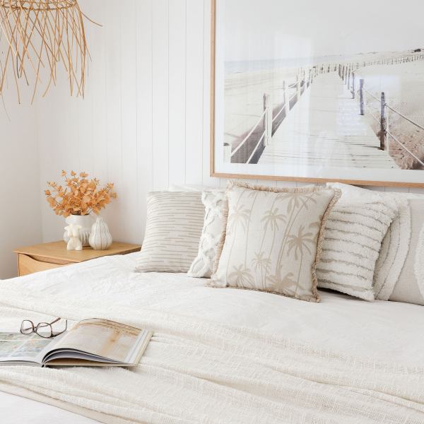 Coastal bedroom with neutral decor and beach artwork