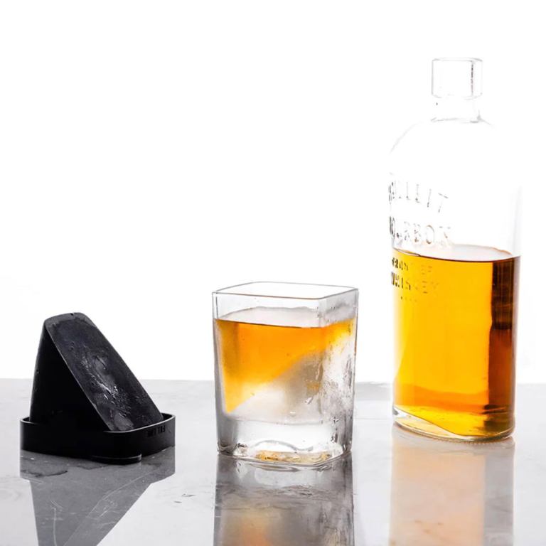 Whisky glass with ice beside bottle
