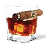 Lit cigar resting on whisky glass with ice