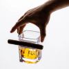 Hand holding whisky glass with cigar