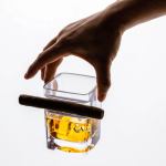 Hand holding whisky glass with cigar
