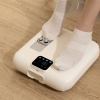 halo percussion foot massager Person using electric foot massager on wooden floor