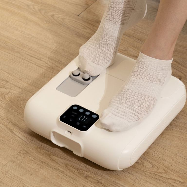 Person using electric foot massager on wooden floor