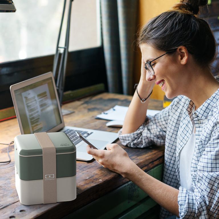 monbento mb square bento box bi colour green Woman using smartphone beside laptop and lunchbox