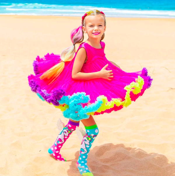 Girl twirling in rainbow dress on beach