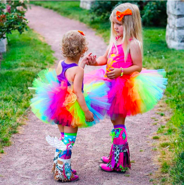 Two children in rainbow tutus holding hands