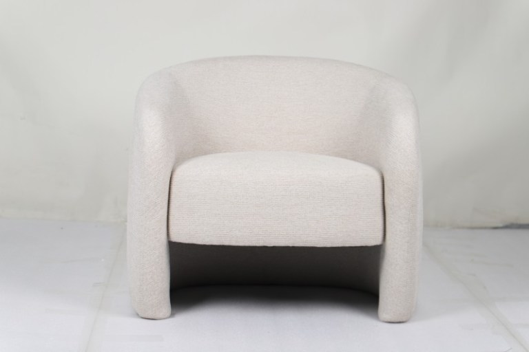 Modern cream upholstered armchair against plain wall