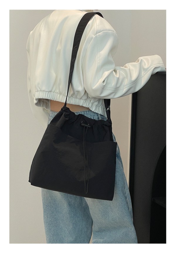 Person wearing black shoulder bag and white jacket