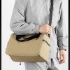 Person wearing grey jacket carrying beige duffel bag