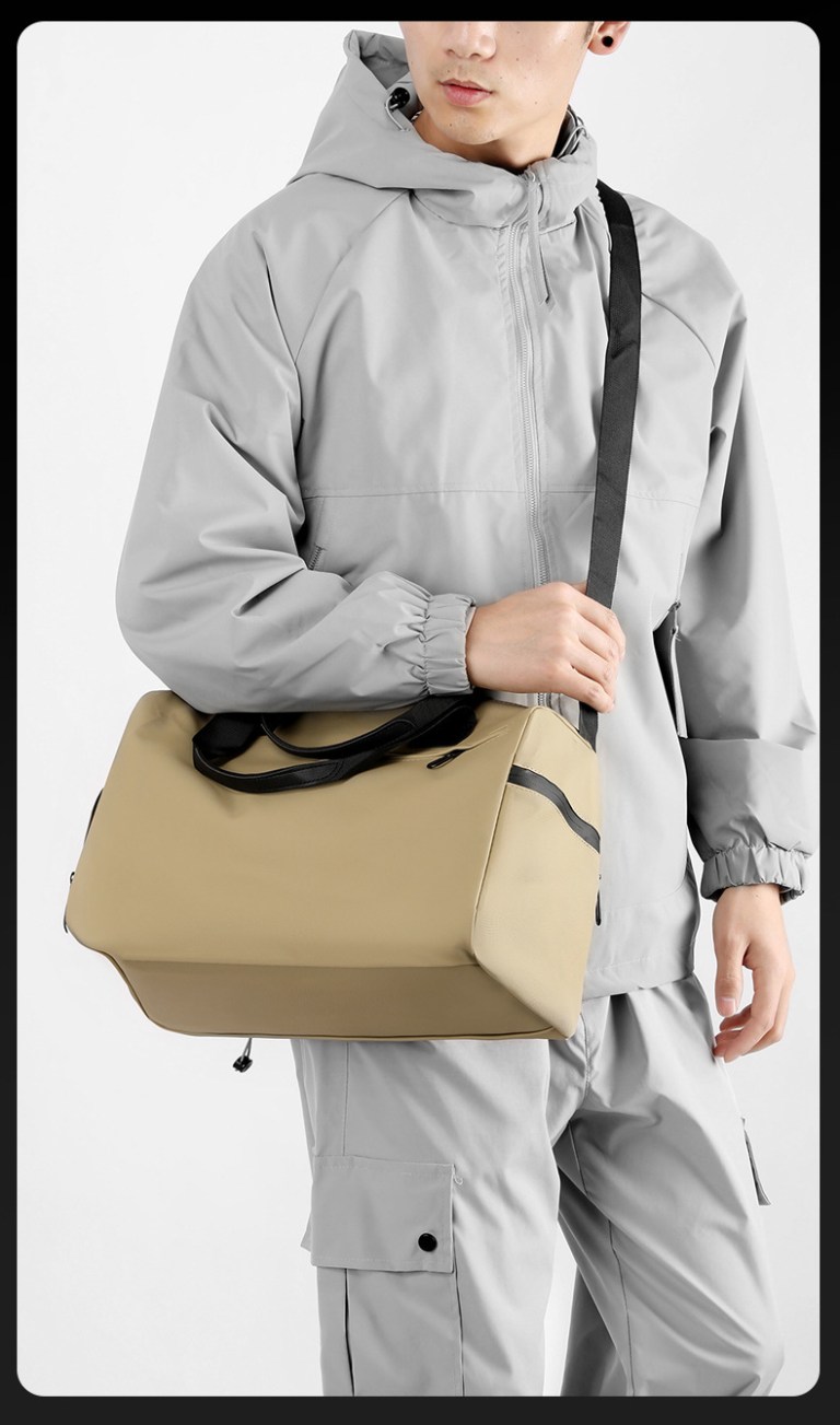 Man wearing grey jacket carrying beige duffel bag