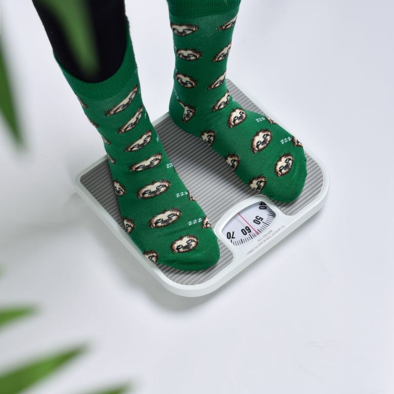 Feet in green sloth socks on scale