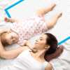 Mother lying beside sleeping baby on mattress