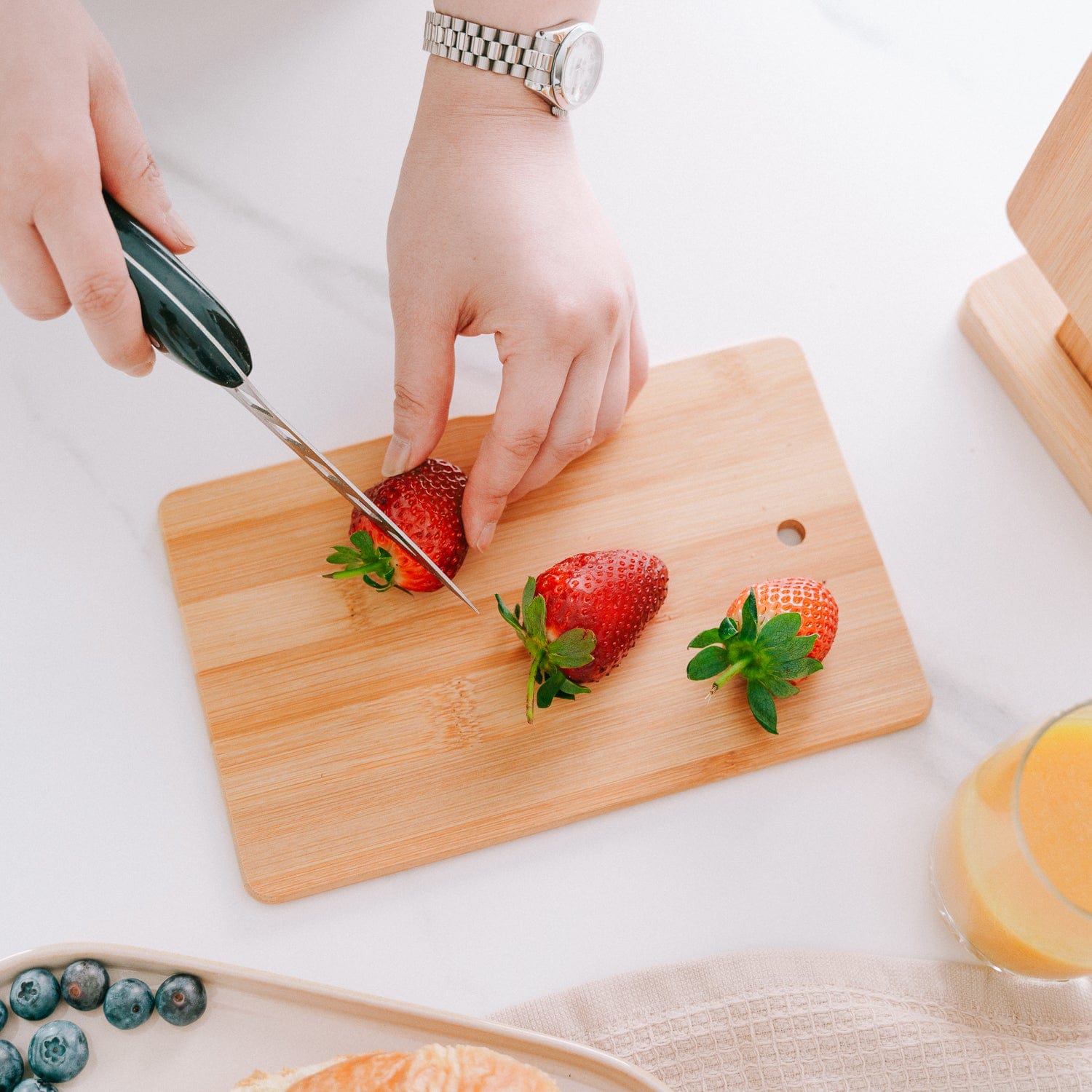Slicing fresh strawberries on wooden cutting board
