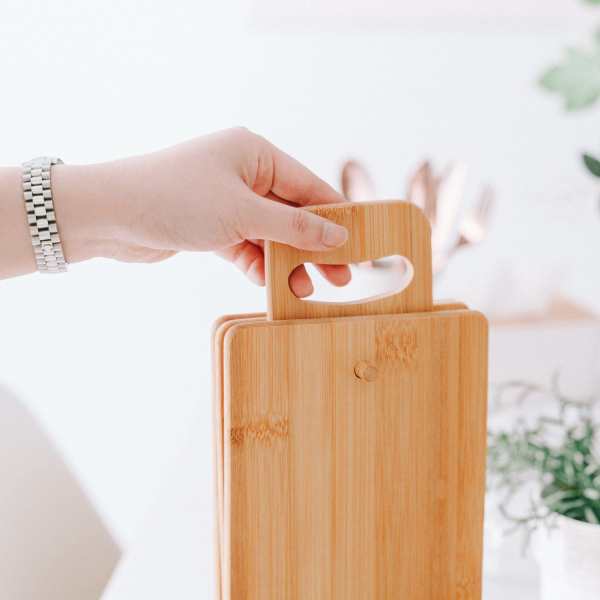 4 piece chopping block set with display Hand holding bamboo cutting board with handle