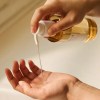 Hand pouring body oil from pump bottle