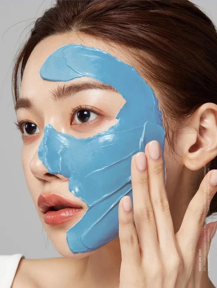 Woman applying blue facial mask skincare treatment